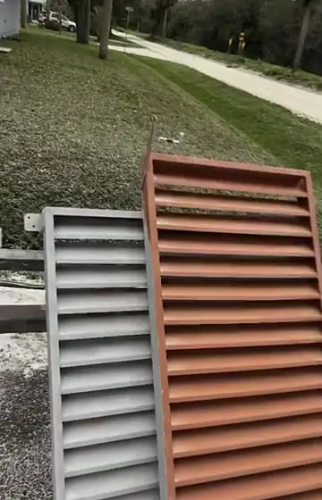 Two steel louver panels, one blasted to bare gray metal and one still covered in old rust-red paint