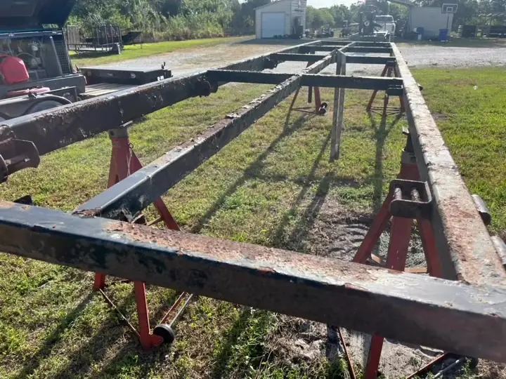 Rusted trailer frame on jack stands before sandblasting, Treasure Coast FL